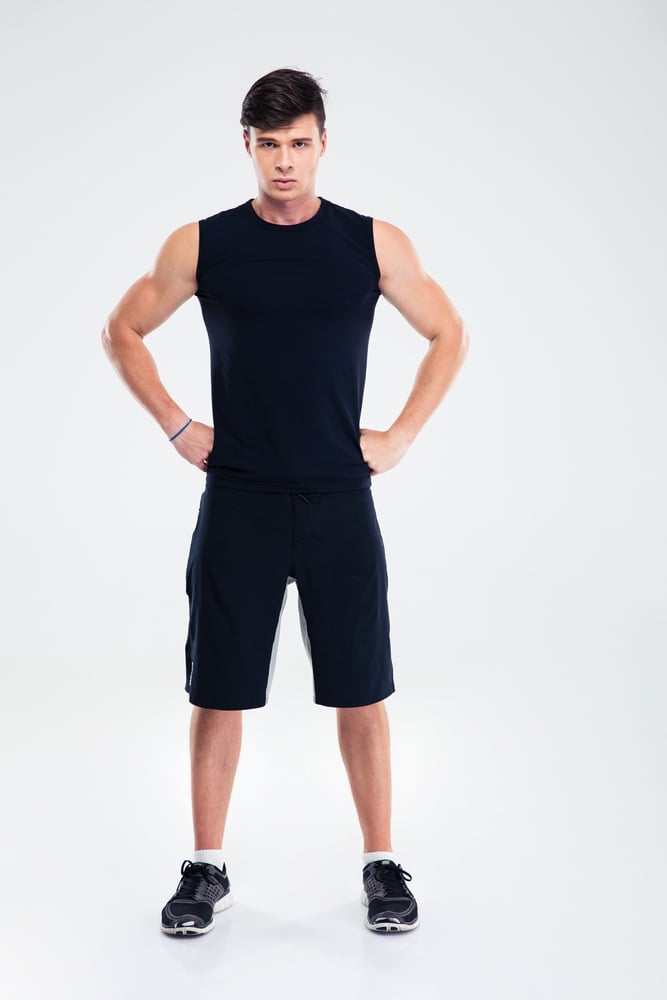 Full length portrait of a fitness man standing isolated on a white background and looking at camera